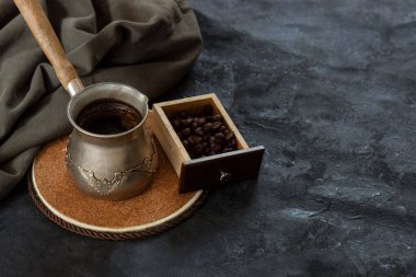 Koyu arkaplanda ahşap bir kutuda kahve çekirdekleri ve yeşil pamuklu kumaşla taze kahve yapan klasik kahve makinesi.