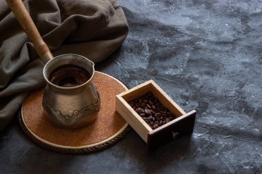 Koyu arkaplanda ahşap bir kutuda kahve çekirdekleri ve yeşil pamuklu kumaşla taze kahve yapan klasik kahve makinesi.