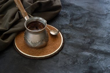 Koyu bir arka planda antika bir kaşık ve yeşil pamuklu kumaşla ahşap tezgahta taze kahve yapan klasik kahve makinesi.