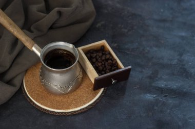 Koyu arkaplanda ahşap bir kutuda kahve çekirdekleri ve yeşil pamuklu kumaşla taze kahve yapan klasik kahve makinesi.