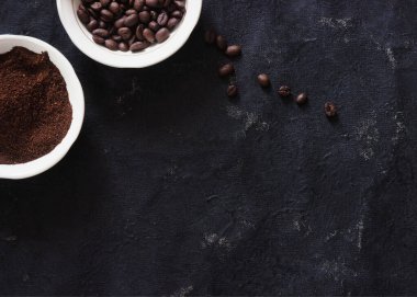 Koyu arkaplanda tabakta kahve ve kahve çekirdeği.