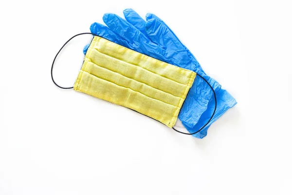 白い隔離された背景にコロナウイルスから保護するための青いラテックス手袋と黄色のマスク — ストック写真