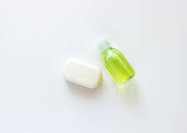 Beyaz, şeffaf bir şişe, sarı-yeşil sıvı ve beyaz bir sabun.