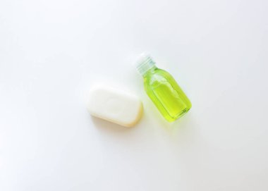 Beyaz, şeffaf bir şişe, sarı-yeşil sıvı ve beyaz bir sabun.