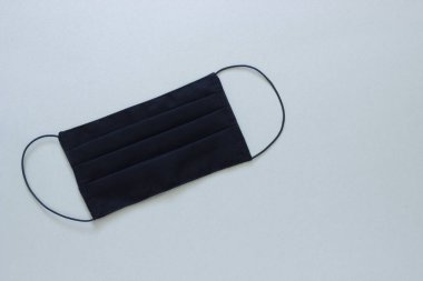 Siyah tıbbi maske, gri arka planda sağlığını virüsten korumak için