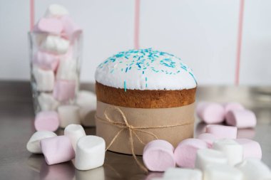 Beyaz bluzlu Paskalya pastası. Mutfak masasında çok renkli şekerlemeler ve şekerlerle süslenmiş.