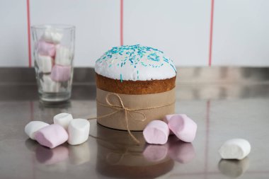 Beyaz bluzlu Paskalya pastası. Mutfak masasında çok renkli şekerlemeler ve şekerlerle süslenmiş.