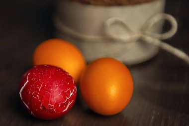 Çatlamış Paskalya yumurtası, diğer renkli yumurtalar ve ahşap masada Paskalya pastası.