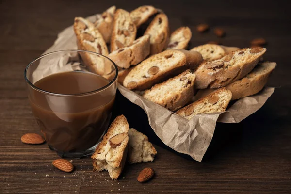 Homemade Italian cookies cantuccini with almond seeds in metal box on brown crumpled paper with glass of cocoa drink