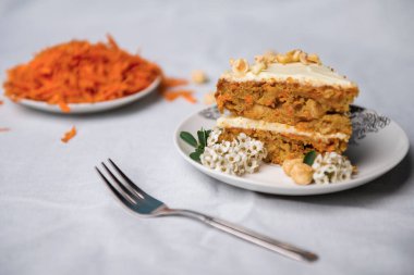 Beyaz bir masa örtüsünde rendelenmiş havuçla süslenmiş havuçlu kek.