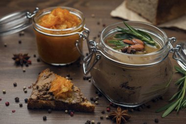 Kümes hayvanı ezmesi ve turuncu gam ile bir dilim ekmek, kümes hayvanları ezmeli cam kavanoz, badem ve biberiyeyle süslenmiş, ve ahşap bir masada turuncu reçelli kavanoz. Baharatla dekore edilmiş ev yapımı ciğer ezmesi.