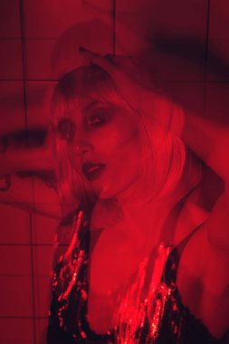 Mor dudaklı, pembe saçlı, banyo arkaplanı kırmızı stüdyo ışığı olan güzel moda kızının yakın plan yüzü.