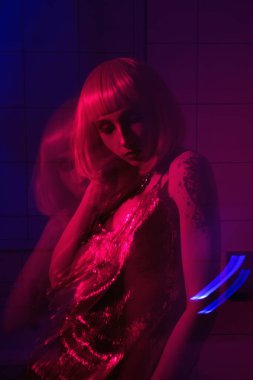 Mor dudaklı, pembe saçlı, kırmızı ve mavi renkli, banyo arkaplanı olan güzel bir moda kızı.