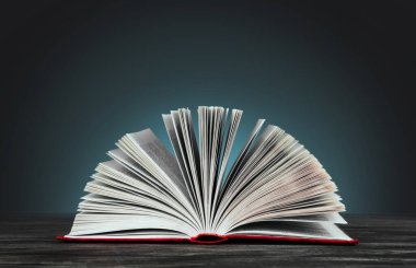 Mavi arka plan fotokopi alanı üzerinde kırmızı kapaklı açık bir kitap. Kitap ahşap bir masada..