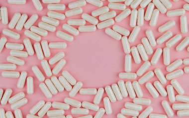 Pembe arka planda beyaz haplar. Dağınık tabletler. Hapların çerçeve kopyalama alanı.