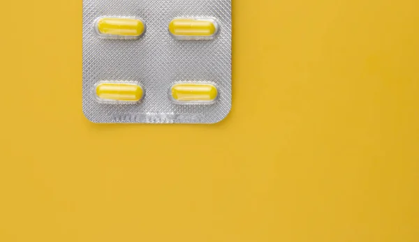 Gelbe Pillen Einer Blisterverpackung Auf Gelbem Hintergrund — Stockfoto