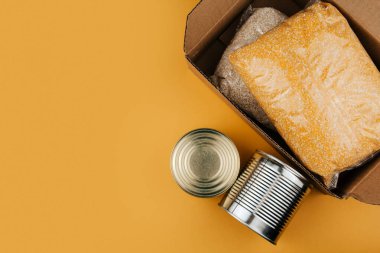 Sarı arka planda bağışlanacak ürünler. Sebzeler, tahıllar ve konserve yiyecekler. Gıda bağışları alanı kopyaladı.