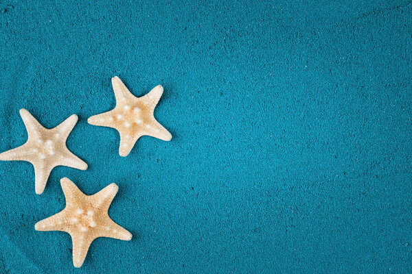 Starfish on the blue sand copy space. Colored sand.