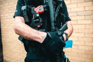 Saldırı tüfeği ve telsizi olan silahlı bir polis.