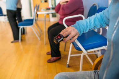 Parmağında kalp atış hızı monitörü olan yaşlı bir hasta.