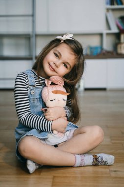 Güzel küçük kız oyuncakla oturuyor.