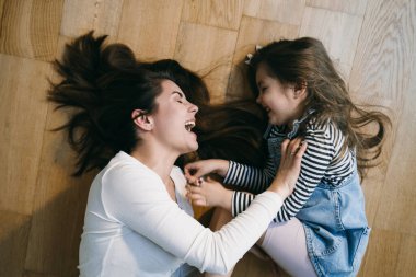 Anne yerde kızıyla oynuyor.