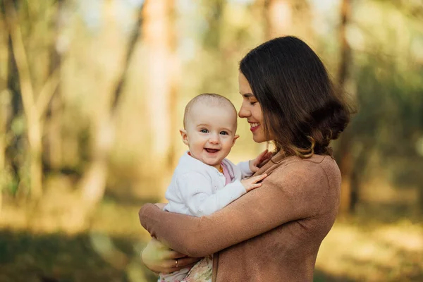 Anne ormanda küçük tatlı bir kız çocuğu tutuyor, aile bahar fotosferi dışarıda, gün ışığında.