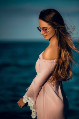 Genç, güzel, güzel bir yüz modeli akşam kumsalında poz veriyor.