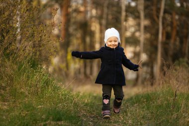 Küçük, güzel bir kız çimenlerde gözleri kapalı koşuyor.