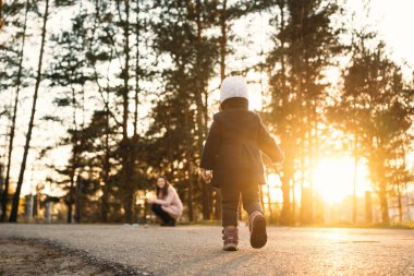 Gün batımının güzel ışığında küçük bir kız annesine doğru koşuyor.