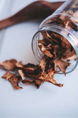 Beyaz arka planda cam bir kavanozda porcini mantarları.