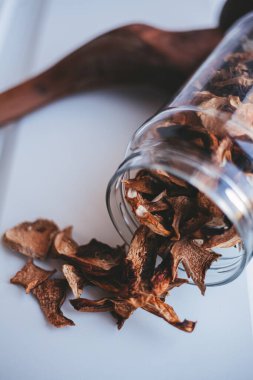 Beyaz arka planda cam bir kavanozda porcini mantarları.