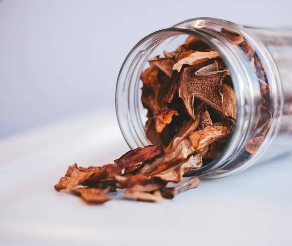     Beyaz arka planda cam bir kavanozda porcini mantarları.