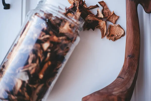 Beyaz arka planda cam bir kavanozda porcini mantarları.