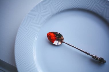 Beyaz arka planda kaşıkta kırmızı biber