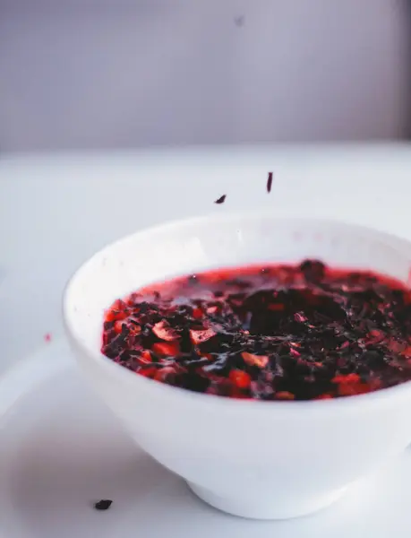 Hibiscus, beyaz arka planda beyaz cam bir fincanda, bir bardakta çay demledi.