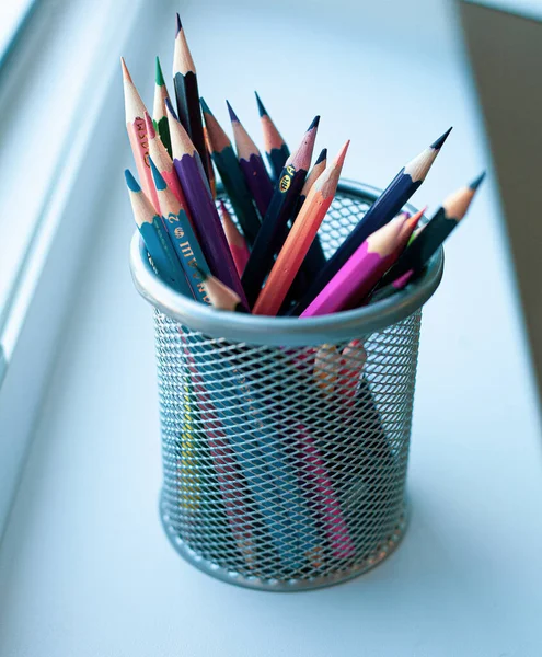 Beyaz arka plandaki bir evin pencere eşiğinde renkli kalemler