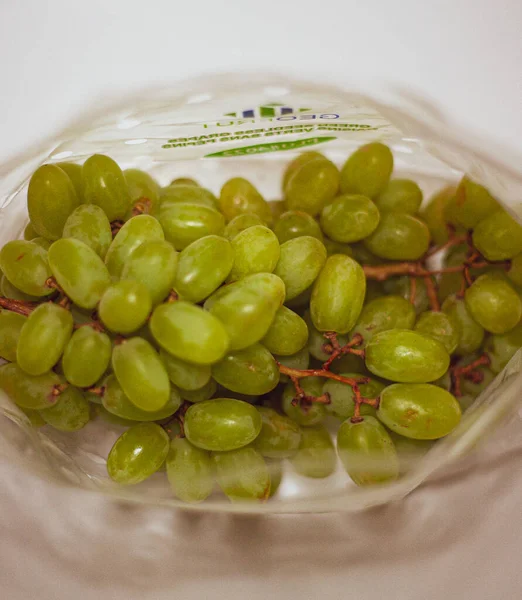 Üzümler beyaz arkaplandaki paketin içinde yatıyor