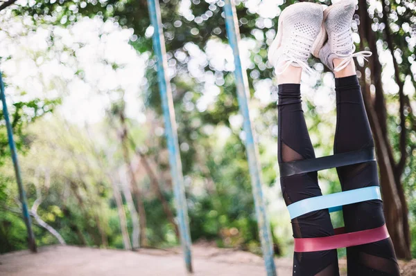 Atletik bir genç kızın bacaklarında üç spor elastik bant var.