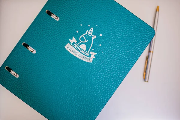 Doku ve gümüş unicorn içeren mavi defter, beyaz arka planda kalem, eğitim arka planı, evde kal.