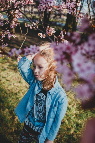 cute sad girl with disheveled hair on a Sunny day. natural beauty, a delicate girl\'s face, naturalness, a teenager, a daughter stands on the street in the spring. European child in a blooming Park, the concept of a happy childhood and the aroma of ch