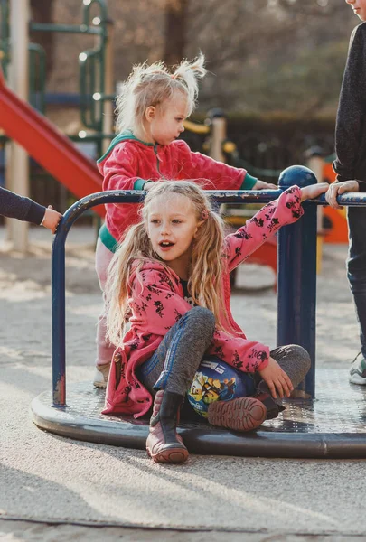 Atkuyruklu sevimli Avrupalı bir kız güneşli bir bahar gününde bir Avrupa parkında oyun oynuyor.