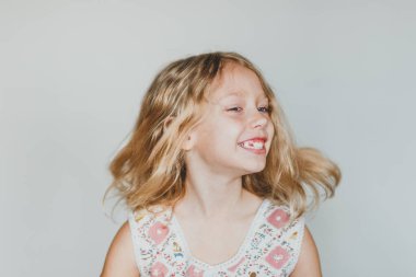 Avrupalı sarışın kız gri arka planda çilek yiyor. beyaz dişler.