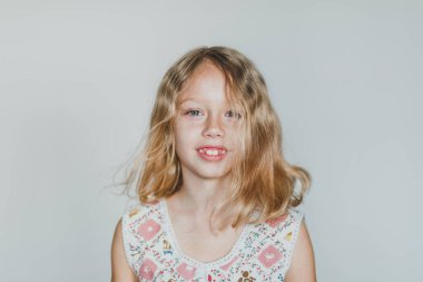 Avrupalı sarışın kız gri arka planda çilek yiyor. beyaz dişler.