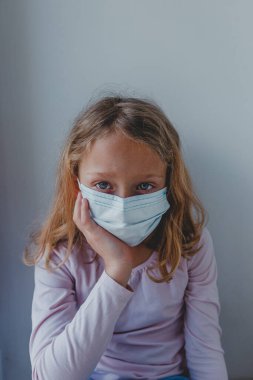 Karantinada maske takmış üzgün bir kız mavi gözlü. portr