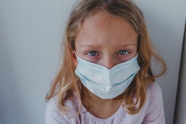 Karantinada maske takmış üzgün bir kız mavi gözlü. portr