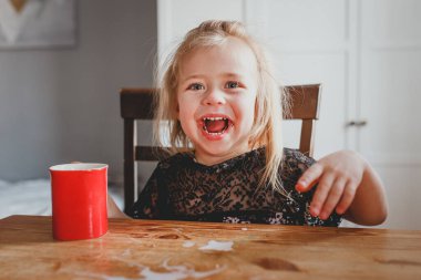 Küçük kız gülümsüyor ve beyaz sağlıklı bebek dişleri parlıyor.