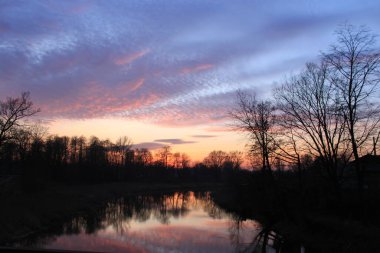 Nehir kıyısında ağaçlarla gün batımı