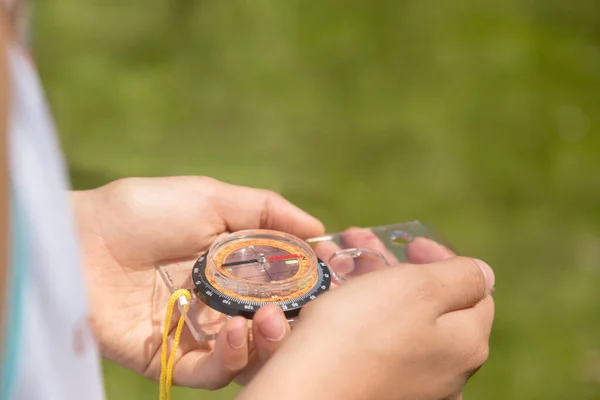 Pusulayı bulanık yeşil arkaplanda tutan eller. Seyahat, rehberlik ve yönelimin kavramsal görüntüsü