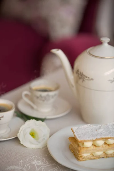 Sıcak çay, porselen çaydanlık ve masanın üzerinde beyaz bir çiçek olan limonlu kurabiyelere yakın çekim. Çay evi. Metin için boş boşluk